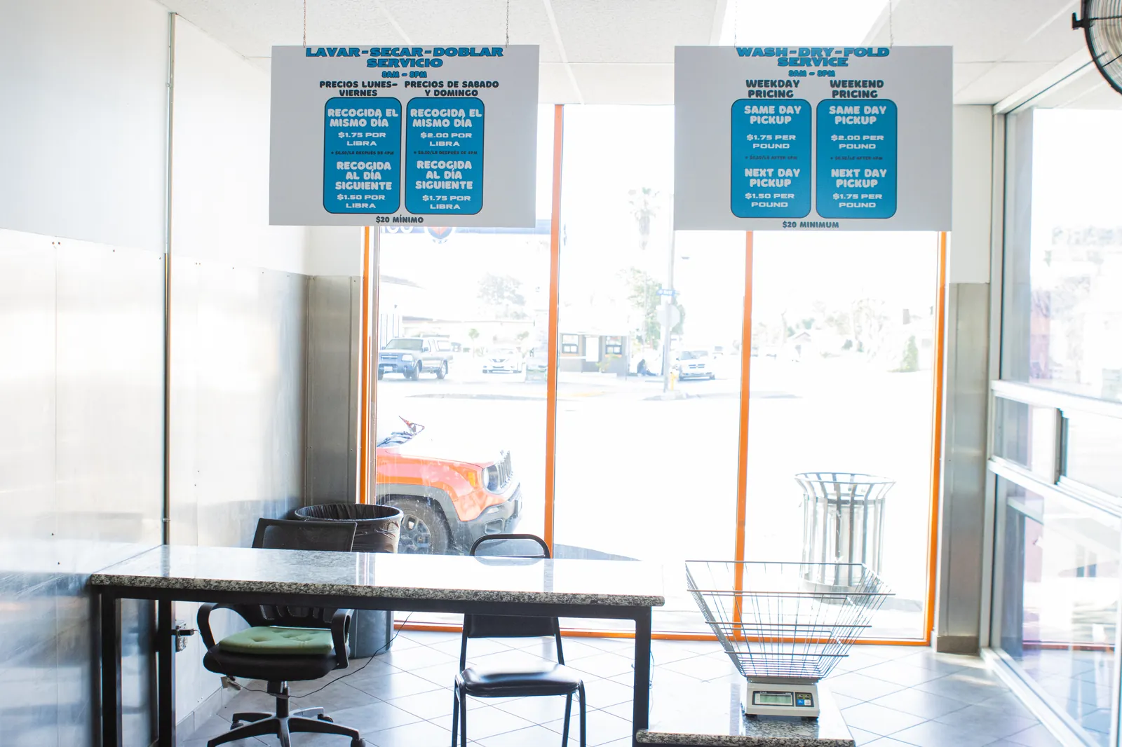 Bilingual wash-dry-fold pricing signs at CleanMax Laundromat drop-off counter in Pomona, CA